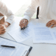 two Healthcare Insurance Brokers discussing margins and looking over paperwork in an office