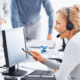blonde customer service representative sitting in front of computer at her desk providing support