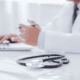 a doctor typing on a laptop with a stethoscope